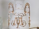 a white and gold vase sitting next to a lamp on a table