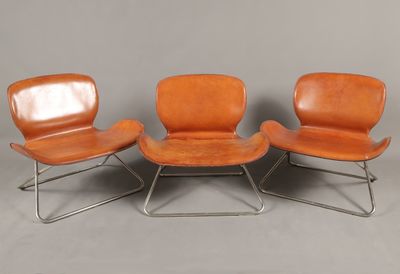 trois fauteuils en cuir orange et une table basse sur fond gris