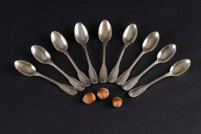 six silver spoons with nuts on a black background