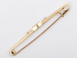 a gold pin with pearls on it