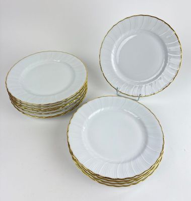 four white plates with gold rims stacked on top of each other