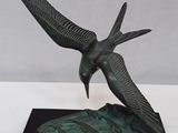 statue of a bird on a black base with a white background
