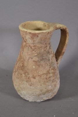 a small brown vase with a handle on a table