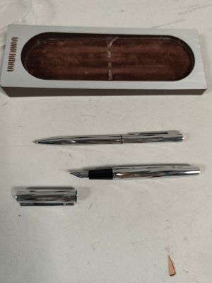 two pens and a pencil in a box on a table