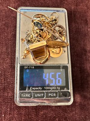 a digital scale with a bunch of gold coins on it