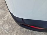 the rear end of a white car with a red tail light