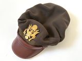 chapeau en cuir marron orné d'un emblème doré sur le dessus, sur un fond blanc