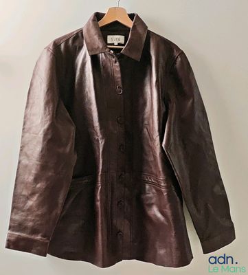 une veste en cuir marron suspendue à un cintre devant un mur blanc
