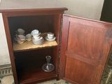 a small cabinet with dishes and cups inside of it