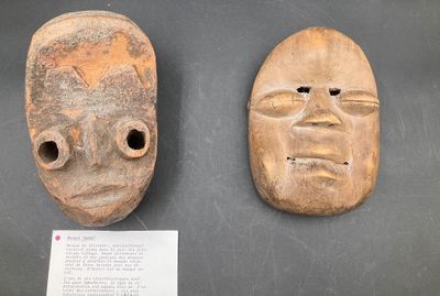 two wooden masks are on display on a black surface