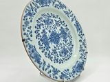a blue and white plate sitting on top of a metal stand