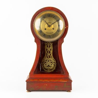 une horloge rouge avec un cadran doré sur fond blanc