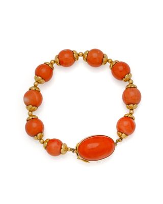 un bracelet en perles orange rehaussé de touches dorées sur fond blanc