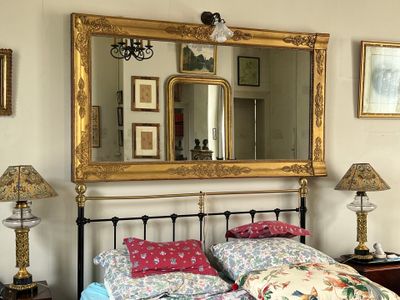 un lit avec une couette à motifs floraux et un miroir au-dessus