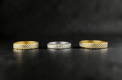 three gold and silver rings on a black surface