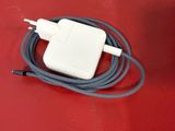 an apple power adapter plugged into a charger on a red surface