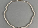 un collier de perles blanches avec un fermoir en or