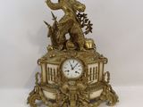 a gold clock with a statue of a man on top of it