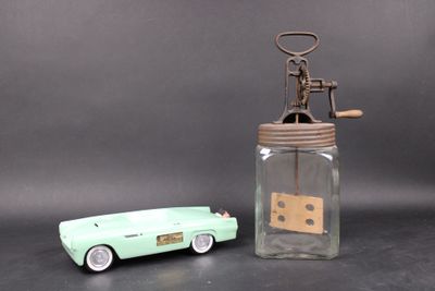 a green toy car next to a glass jar with a corkscrew
