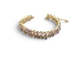 a gold bracelet with pink stones on a white background
