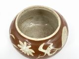 a brown and white bowl on a white surface