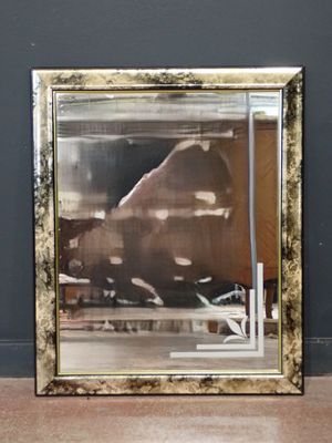 un grand miroir posé à même le sol devant un mur noir