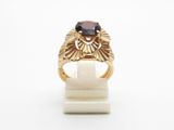 a close up of a gold ring with a red stone