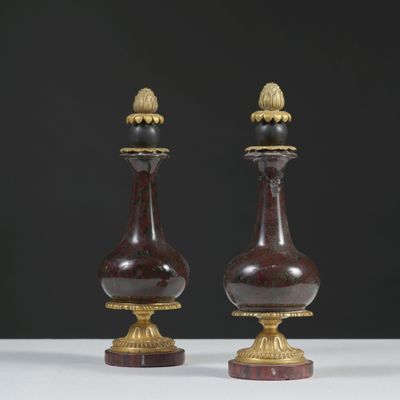 une paire de vases rouges et dorés posés sur une table blanche