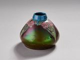 un vase violet et vert orné de fleurs, posé sur un fond blanc