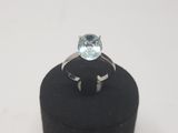 a ring with a blue topaz stone sits on a black ring stand