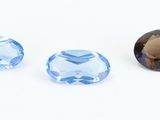 three different sizes of blue topazte stones on a white surface