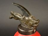 a red fire hydrant with a bronze statue of a dragon on it