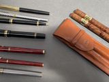 de nombreux stylos et un étui à stylos posés sur une table