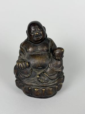 statue of a laughing buddha sitting on a rock with a child