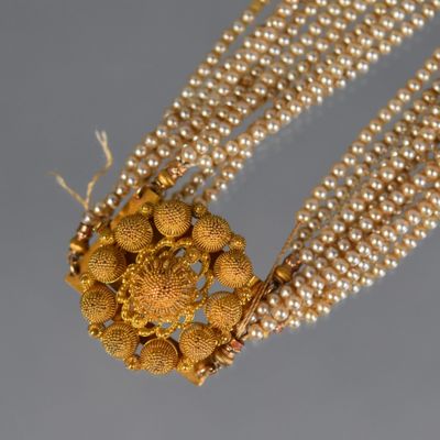 a close up of a necklace with pearls and gold beads