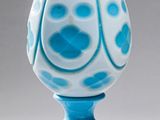 vase en verre bleu et blanc, avec un socle doré sur fond blanc