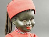 a black doll with a red shirt and a red hat