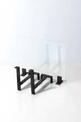 une table en verre avec une base en métal et un plateau en verre