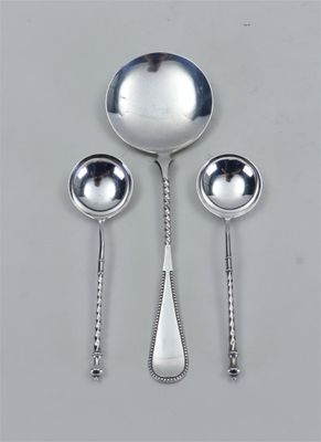 trois cuillères en argent et une cuillère dont le manche repose sur une table