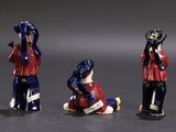 three figurines of people sitting on the ground, one holding a cell phone to his ear and the other holding a cell phone to his ear