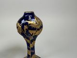 a blue and gold vase sitting on a white surface