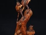 une sculpture en bois représentant un cerf et un chat sur un rocher