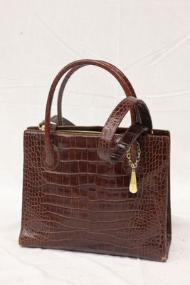 un sac à main en peau de crocodile marron avec une chaîne en or