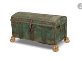 a green trunk sitting on wheels on a white surface