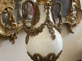 a white and gold vase sitting on a table in front of a mirror