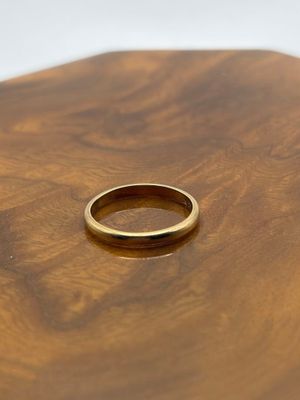 un gros plan d'une alliance en or posée sur une table en bois
