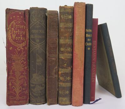 several old books are stacked on top of each other on a white surface