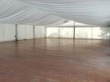 a large white tent with curtains and wood flooring