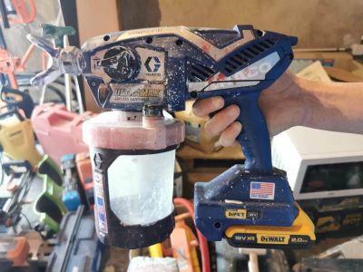 une personne qui utilise un pistolet à peinture pour peindre un meuble