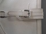 a close up of a white purse with a metal buckle